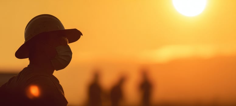 The silhouette of a worker at sunset wearing a helmet and mask photo