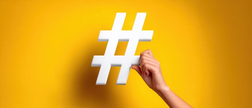 The hashtag symbol held by a hand against a vibrant yellow background. photo