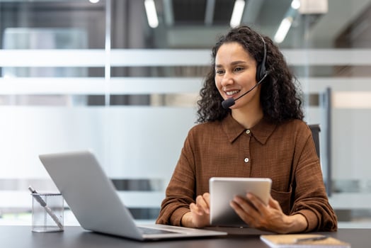 Woman with headset using laptop and tablet photo