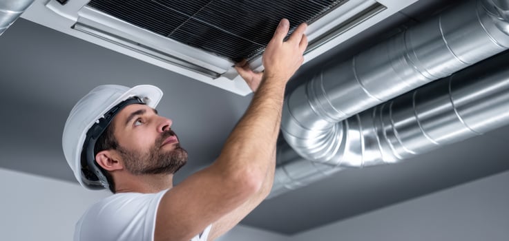 The technician inspecting the air conditioning unit in a modern commercial space. photo