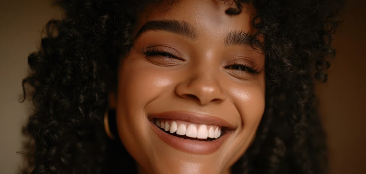 The radiant smile of a woman with curly hair in soft lighting. photo