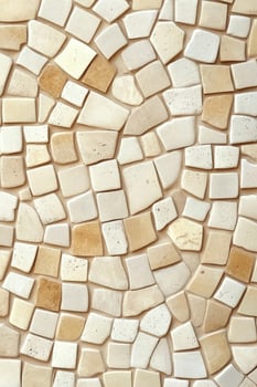 Irregular shaped off white and tan ceramic tiles create a textured surface pattern photo