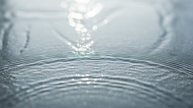 Water droplets on a surface with a sun shining through photo