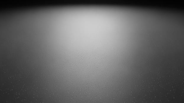 sl a ck a nd white photo of a light shining on a d a rk surf a ce