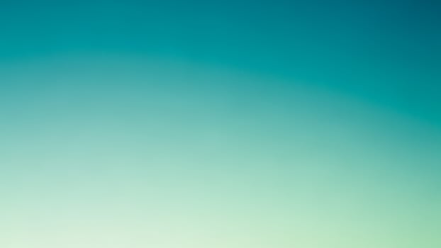 A blue and green blurred background with a plane flying over it photo
