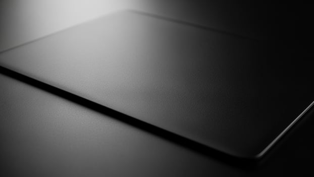 A black laptop on a table with a light shining on it photo