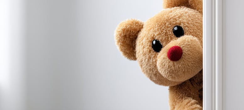 The adorable teddy bear peeking from behind a doorway in a cozy room photo