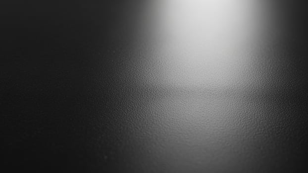 Black and white photo of a light shining on a black surface