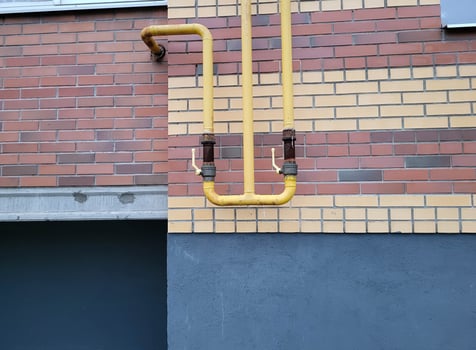 Yellow gas pipes on the wall of a red brick house. photo