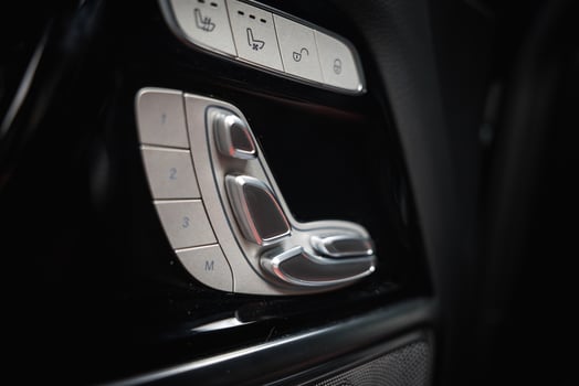 Metallic seat adjustment controls with memory and heating buttons in a dark luxury car interior, showcasing sleek design and premium craftsmanship. photo