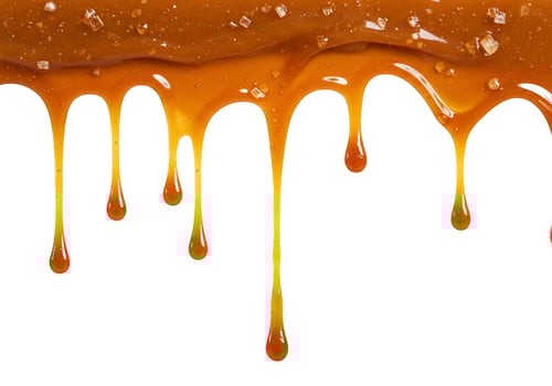 Flowing caramel drips with sugar crystals texture isolated on white background photo
