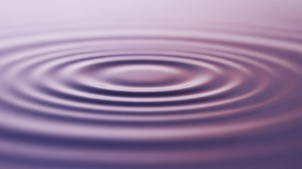 A circular ripple in water with a purple background photo