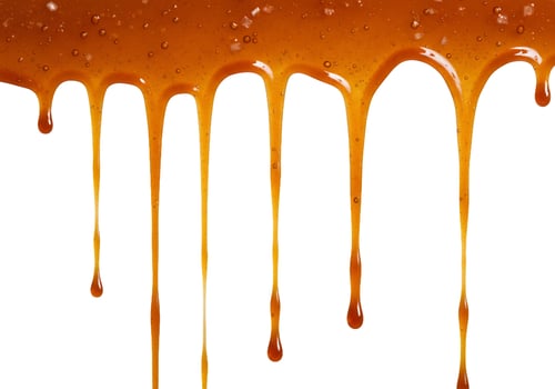 Amber liquid dripping sweet honey or caramel sauce abstract texture photo