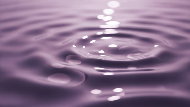 Water ripples on a purple surface with a sun shining photo