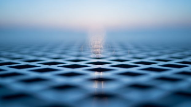 A close up of a metal grid with a light shining through photo