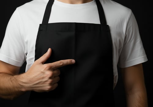 Person wearing apron pointing to center isolated on dark backdrop photo