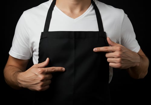Person wearing apron pointing with fingers against dark background photo