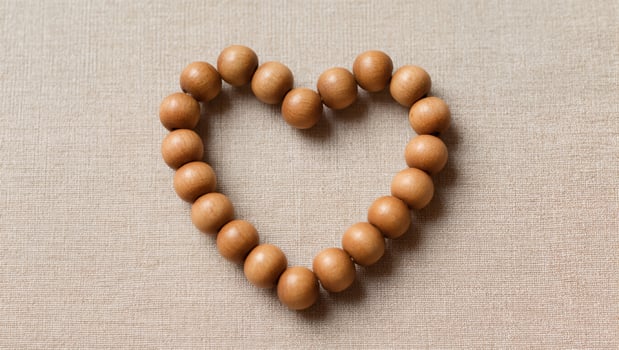 Wooden Beads Arranged in a Heart Shape on a Neutral Fabric Background for Decorative Purposes photo