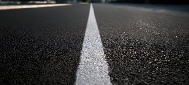 The smooth asphalt road with a prominent white line extending ahead. photo