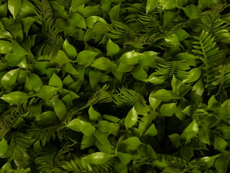 Artificial green wall with lush plastic leaves and foliage texture perfect for eco branding sustainable product backgrounds organic style mockups or vertical garden visuals with green aesthetics photo
