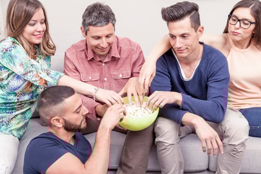 group of friends eating popcorn sitting on the couch photo