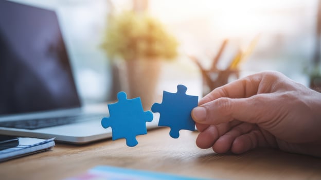 The Hand Holding Two Blue Puzzle Pieces in a Modern Workspace photo