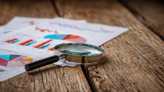The magnifying glass resting on business analytics reports on a wooden desk. photo