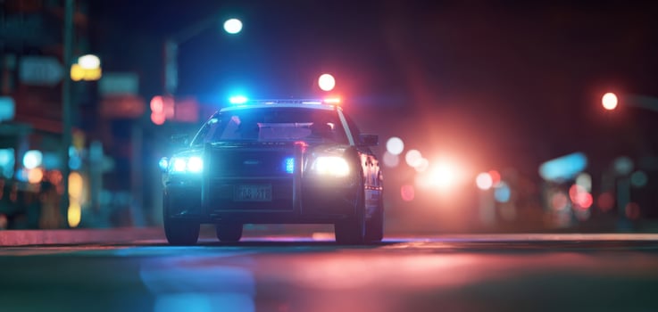 The police car with flashing lights driving through a vibrant urban night scene. photo