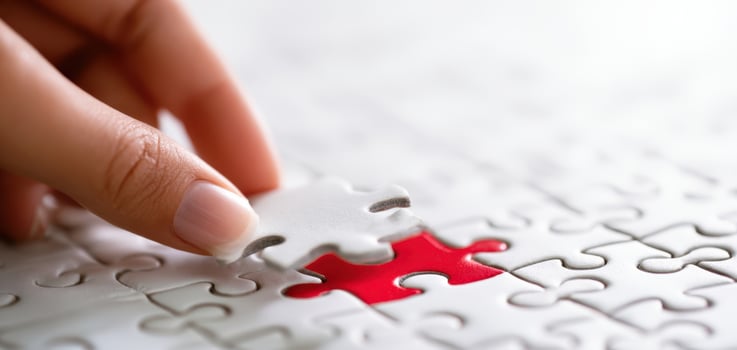 The hand placing a puzzle piece into a red jigsaw section. photo