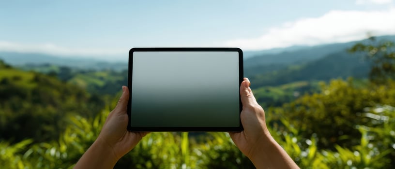 The tablet held in hands against a breathtaking nature landscape. photo