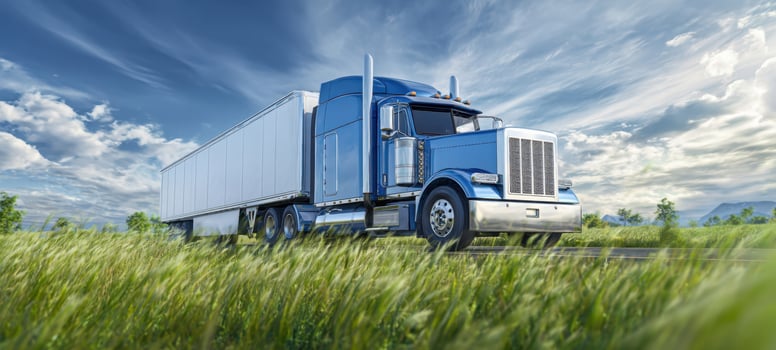 The stunning blue truck driving through a vibrant green landscape under a dramatic sky. photo