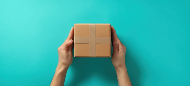 The Hands Holding a Delightfully Wrapped Gift Box on a Teal Background photo