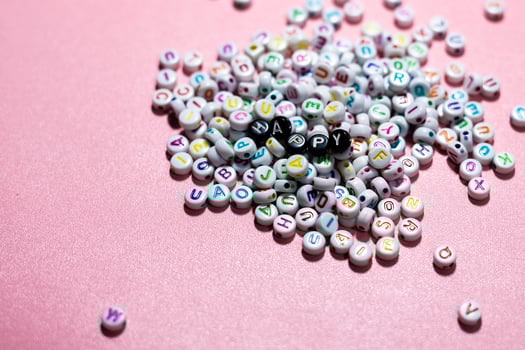 happy lettering with alphabet beads on pink background with copy space. An empty space for banner wallpaper. photo