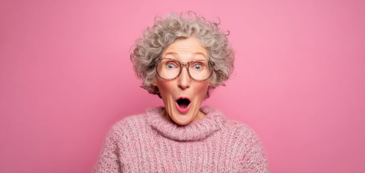 The surprised elderly woman expressing joy with vibrant pink background. photo