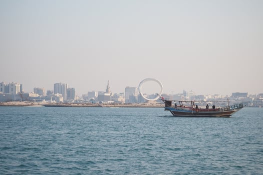 qatar doha 12 march 2025. Traditional boat sails near city skyline in daylight photo
