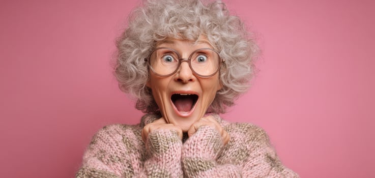 The joyful elderly woman with curly hair expressing excitement against a pink backdrop. photo