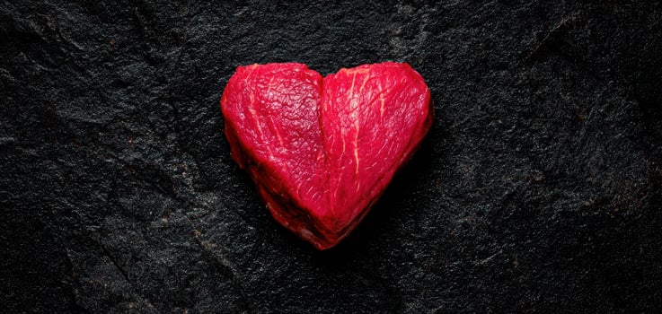 The Heart-shaped Piece of Raw Beef on Dark Background photo