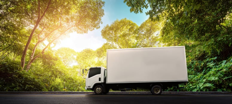 The white truck parked in a lush green forest setting during sunset. photo