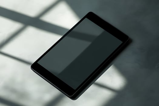 A black tablet sitting on a table with a shadow photo