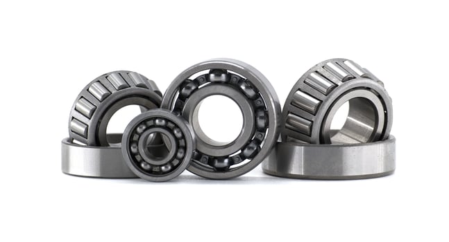 Diverse collection of mechanical ball and roller bearings sits on a clean white surface. photo