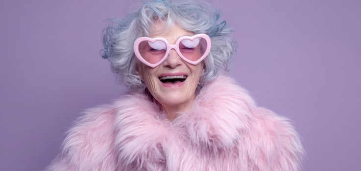 The joyful elderly woman wearing pink sunglasses and a fur coat. photo