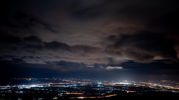 High angle view from Phu Thap Buek to city at night. City lights glow brightly against the dark landscape. While a thick layer of clouds hangs low in the sky. View of Lom Sak Phetchabun Thailand. photo