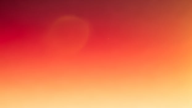 A red and orange blurred background with a plane in the sky photo
