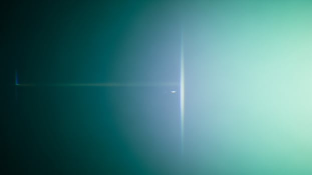 A green and blue light is shining through the dark photo