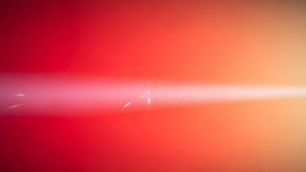 A red and orange light beam is shining through the air photo
