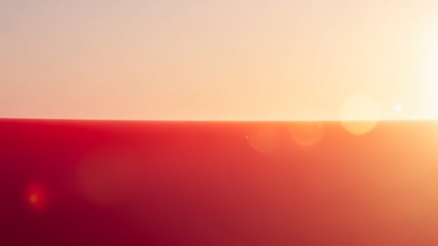 A man is standing on top of a hill with the sun shining photo