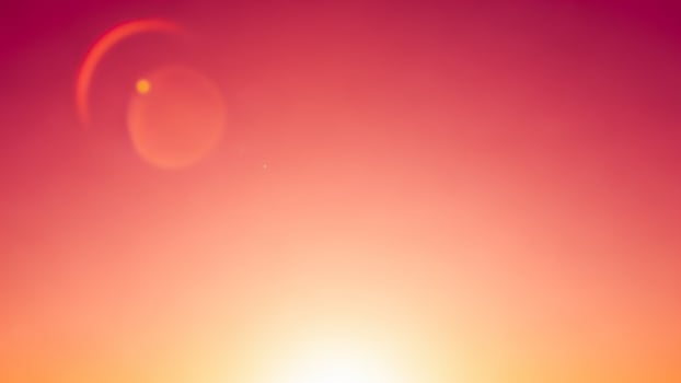 A sunset with a bright orange sky and a bright sun photo