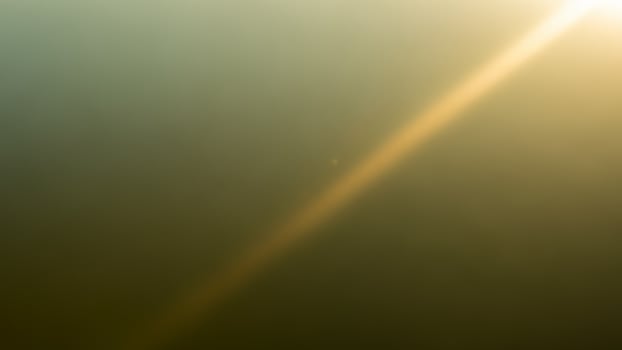 A plane flying over a field with the sun shining photo