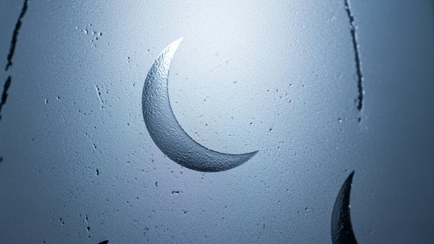 A crescent moon is reflected in a window photo