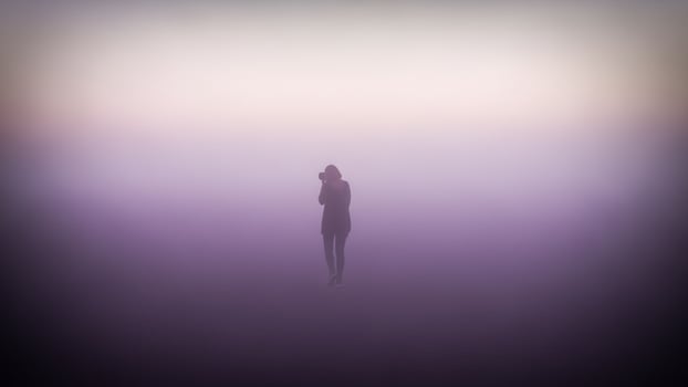 A person standing in the fog with a camera photo